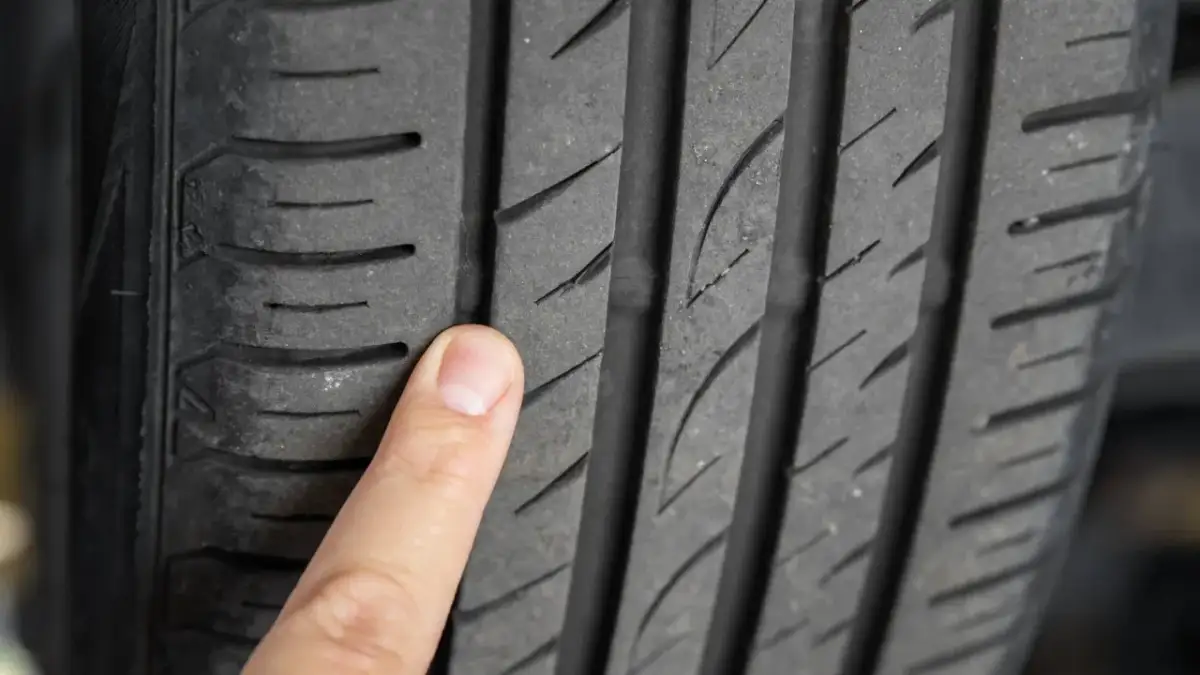 Palec wskazujący na bieżniku opony, uwidaczniający drobne mikropęknięcia.