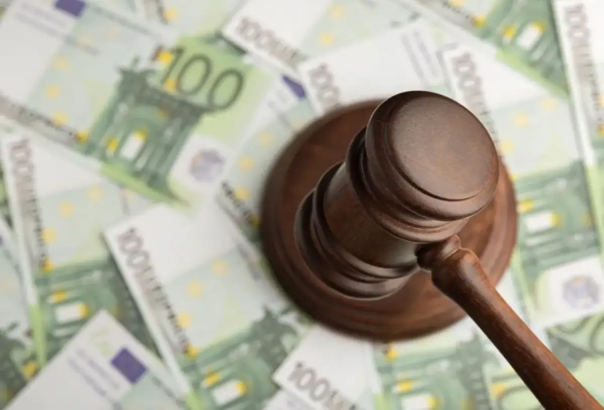 Młotek sędziowski na banknotach 100 euro. Zastanawiasz się, ile kosztuje upadłość konsumencka?