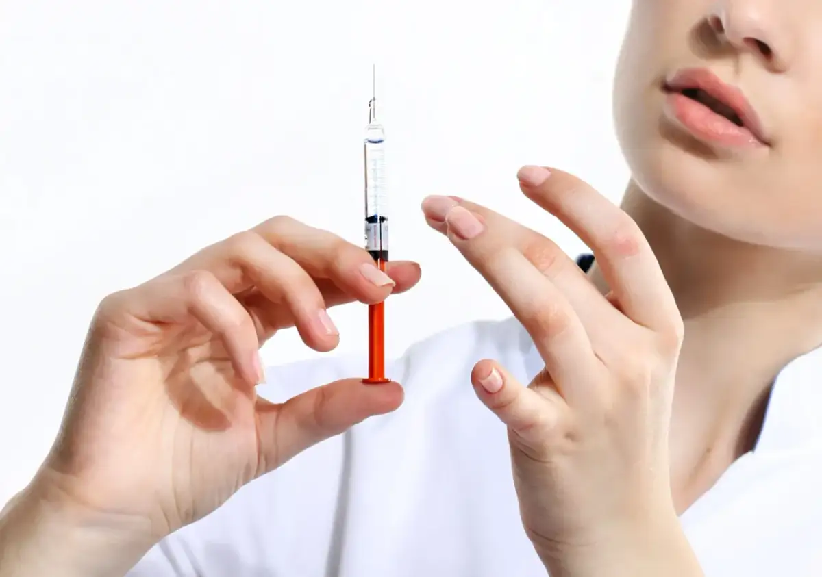 Dłoń trzyma strzykawkę z płynem, gotową do podania. To ważny krok w kierunku szczepień obowiązkowych.