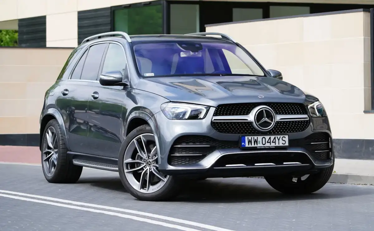 Szary Mercedes GLE 300 d stoi przed nowoczesnym budynkiem. Elegancki SUV z charakterystycznym grillem i felgami.