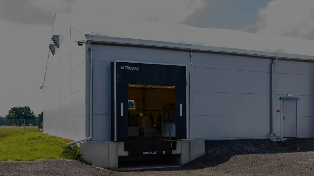 Nowoczesny magazyn z otwartymi dokami przeładunkowymi. Widać rampę i fragment wnętrza z towarami.