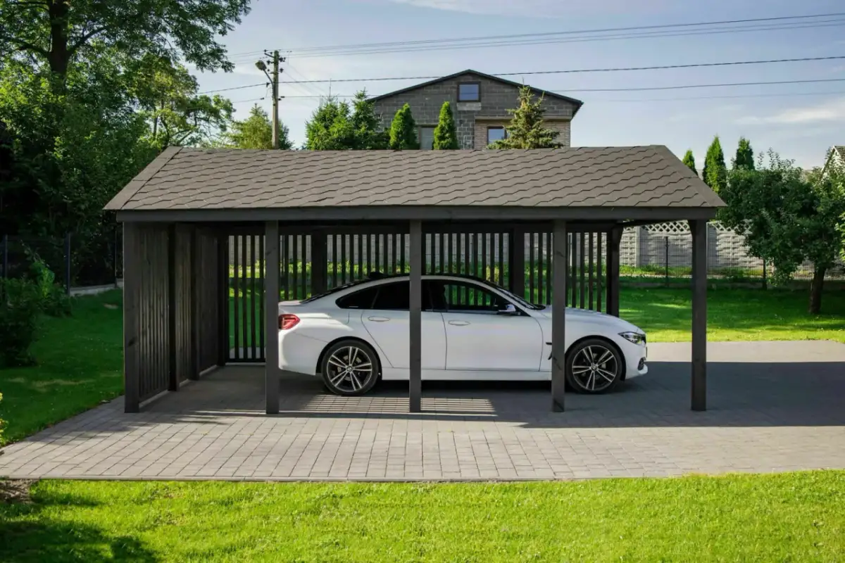 Eleganckie wiaty garażowe drewniane chronią białe auto przed słońcem i deszczem.