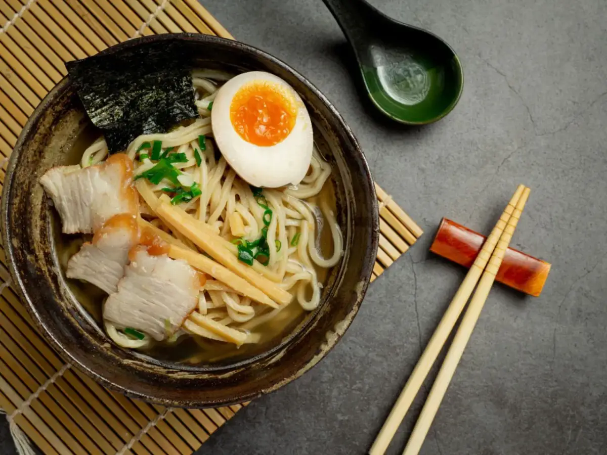 Miseczka aromatycznego ramenu z plastrami wieprzowiny, jajkiem na pół, bambusem i nori. Idealny przepis, jak ugotować ramen.