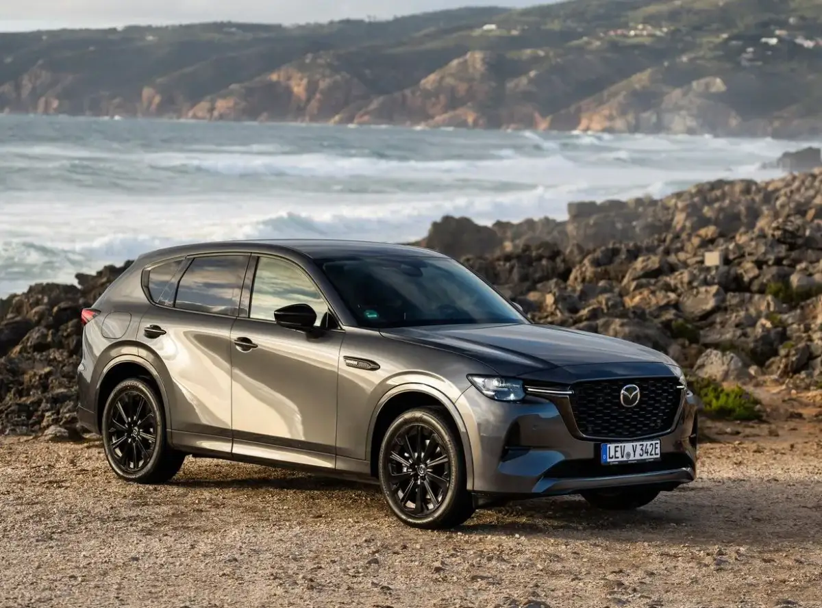Szary SUV Mazda CX-60 na tle skalistego wybrzeża. To jeden z rodzajów hybryd, który łączy moc z ekologią.