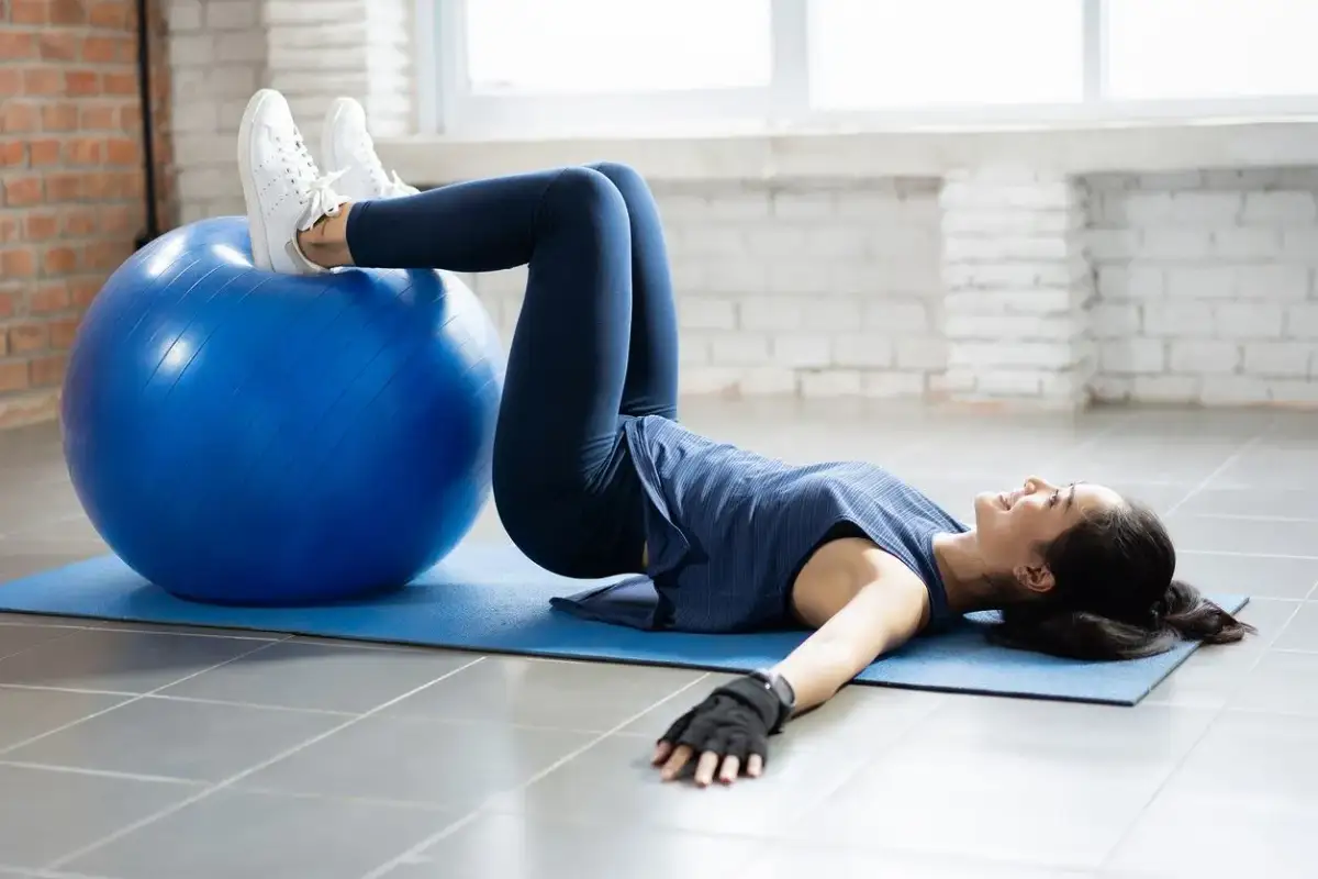 Kobieta wykonuje ćwiczenia na kręgosłup piersiowy z piłką gimnastyczną.