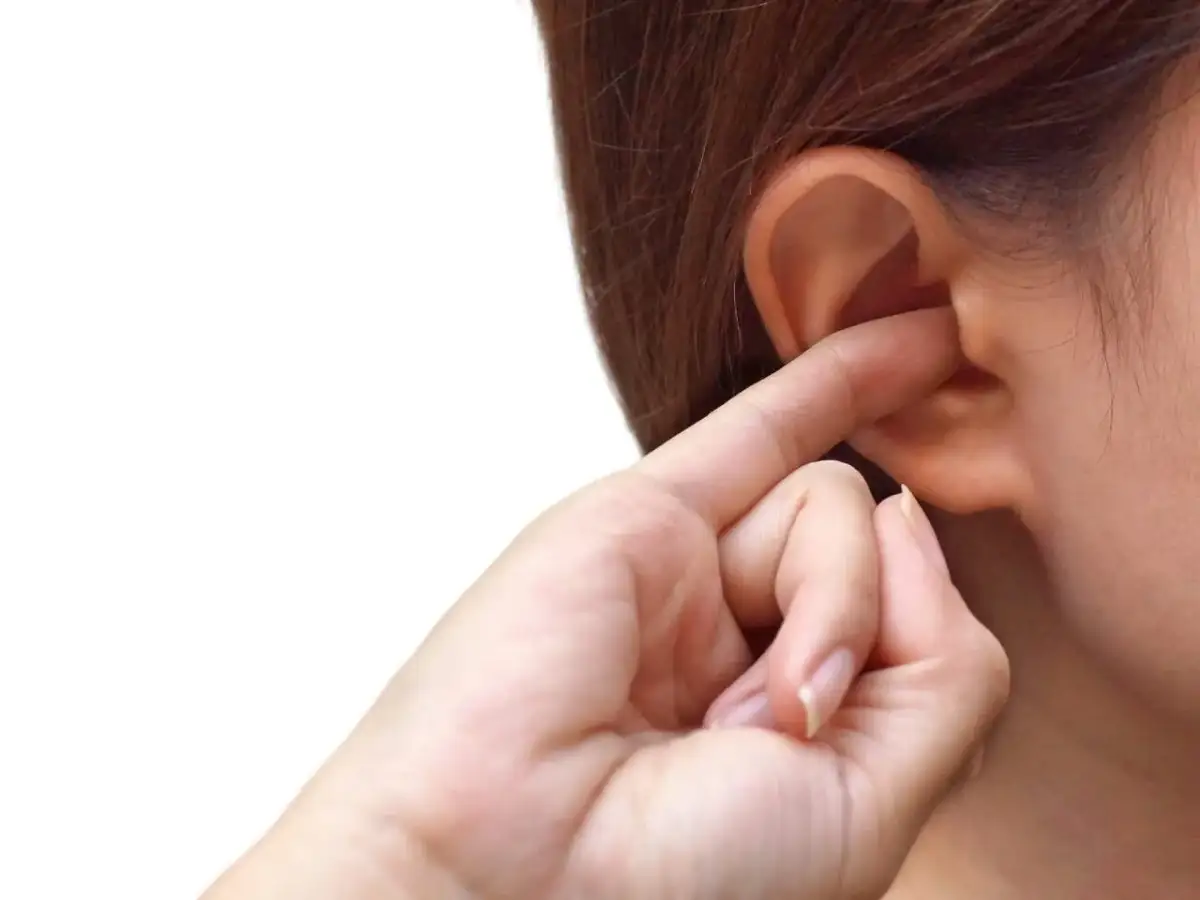 Dłoń z palcem w uchu, próbująca pozbyć się uczucia zatkanego ucha.