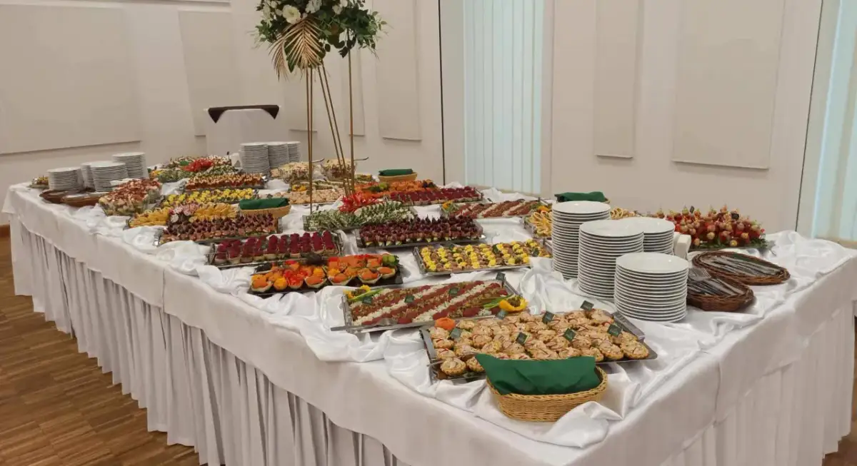 Stół z bogatym cateringiem: przekąski, sałatki, przystawki, talerze i dekoracje.