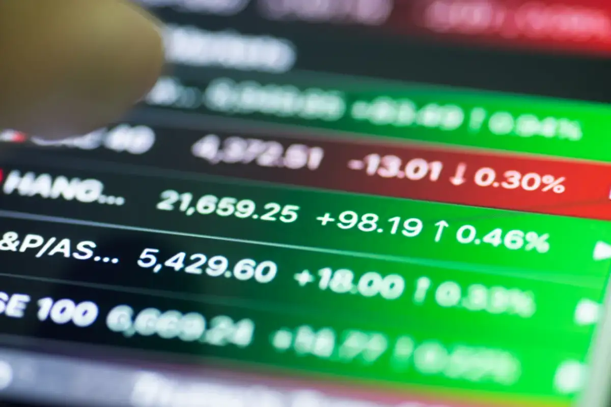 Palec wskazuje na wykres giełdowy. Wiele indeksów rośnie, co oznacza hossa. Co to jest hossa? To okres wzrostów na giełdzie.