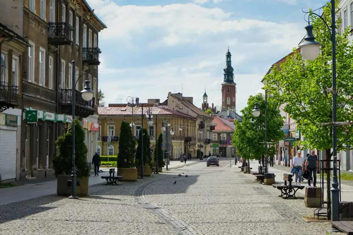Ulica w Radomiu z kamienicami, wieżą kościelną i zielenią.