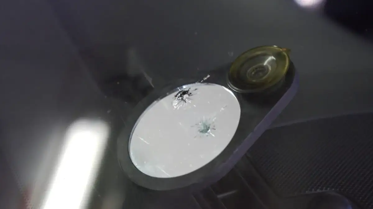 Uszkodzona szyba samochodowa z pęknięciami, czekająca na naprawę.