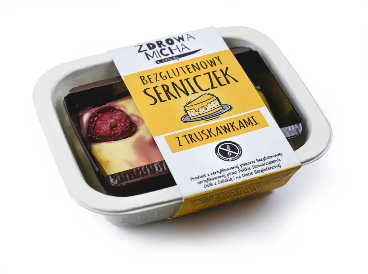Bezglutenowy serniczek z truskawkami w białym opakowaniu.