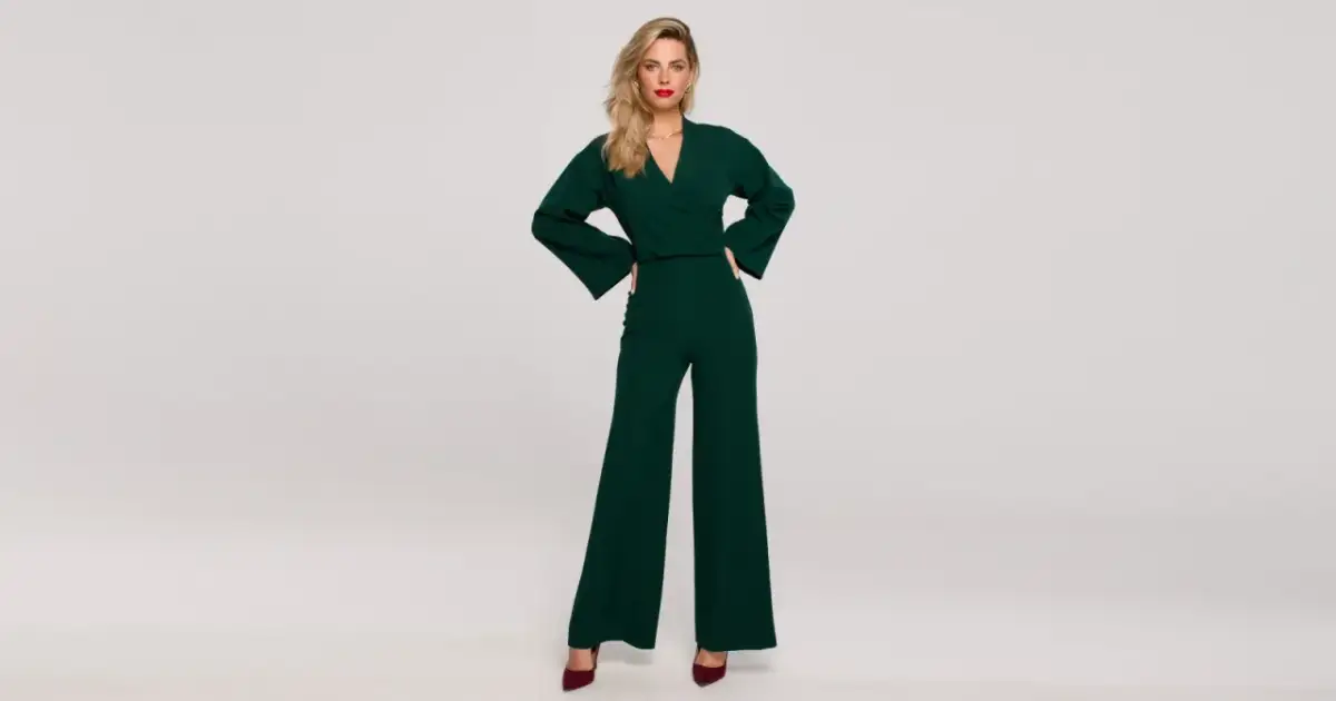 Kobieta w zielonym kombinezonie z szerokimi nogawkami i bordowych szpilkach.