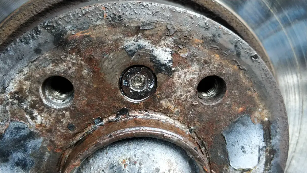 Rdza i zniszczenia na piaście koła, wskazujące na trudności w demontażu. Jak ściągnąć tarcze hamulcowe, gdy śruby są zapieczone?