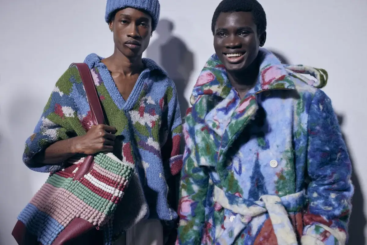 Dwóch młodych mężczyzn w kolorowych, wzorzystych swetrach i płaszczach, niczym Laura i Filon z wiersza Marii Pawlikowskiej-Jasnorzewskiej, pozuje do zdjęcia.