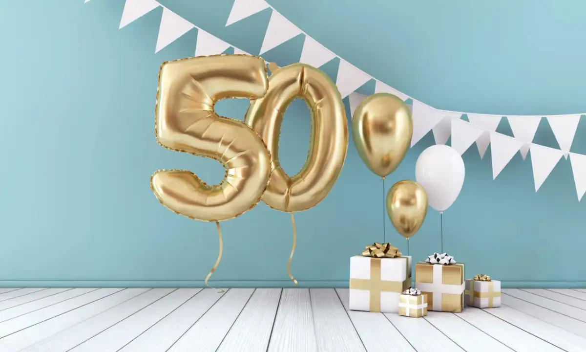 Złote balony z cyfrą 50, prezenty i girlandy tworzą scenę na 50. urodziny. Niech to będzie początek mądrych życzeń na 50 urodziny dla kobiety!