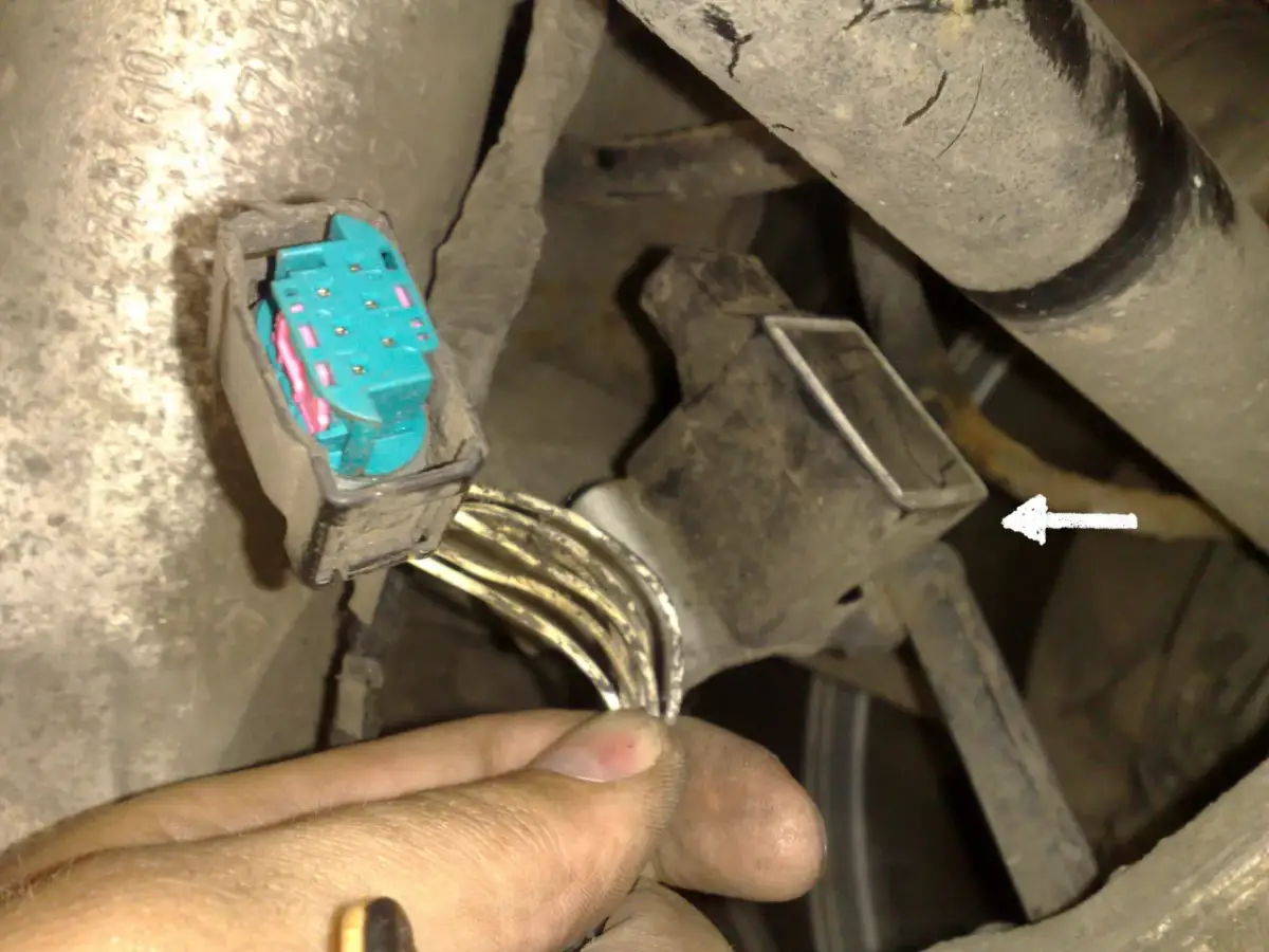 Jak sprawdzić czujnik poziomowania świateł BMW? Widoczny jest zdemontowany czujnik z wiązką przewodów i złączem.