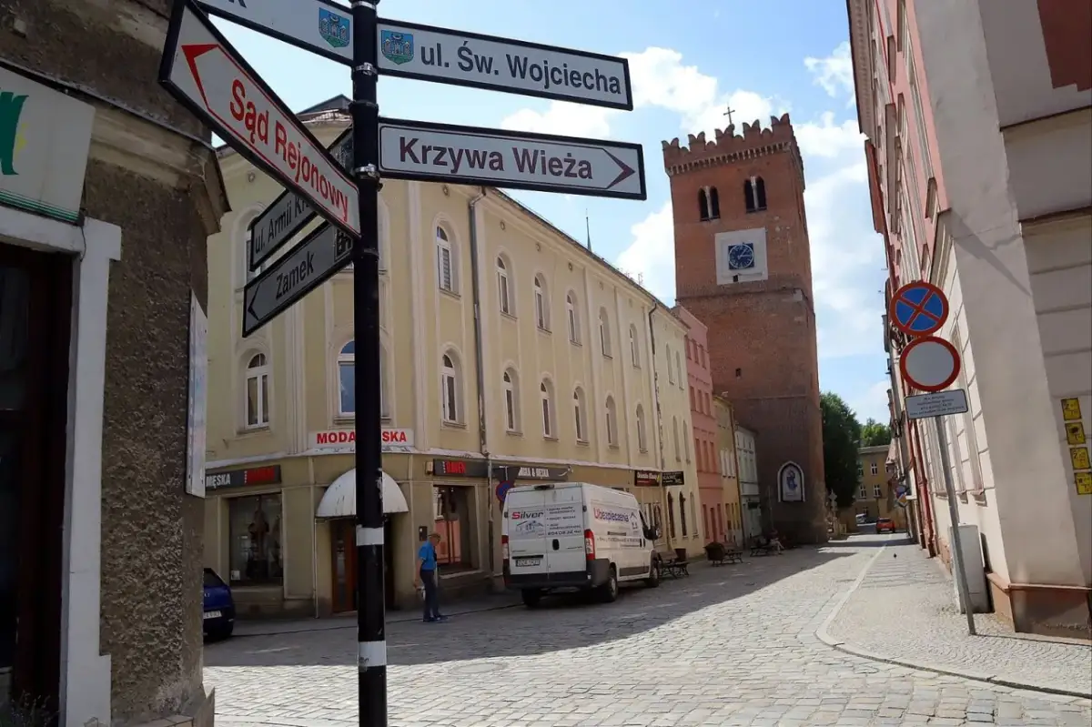 Ulica z wieżą i drogowskazami do Sądu Rejonowego, Krzywej Wieży i Zamku. Odkryj mało znane miejsca na Dolnym Śląsku.