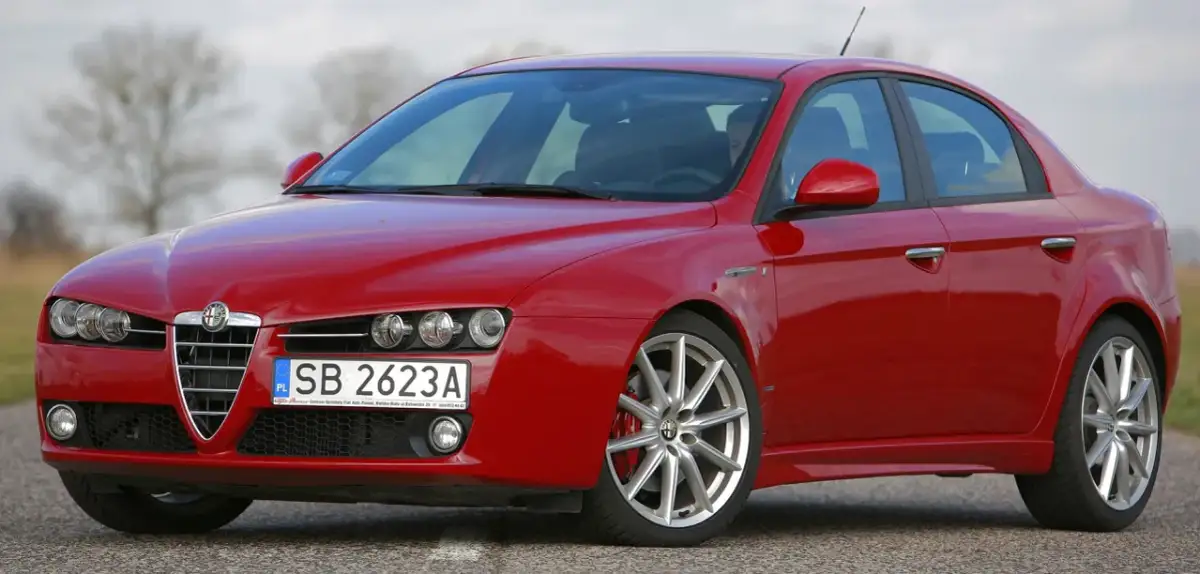 Czerwone Alfa Romeo 159 na drodze. Nawet piękny samochód doświadcza utraty wartości, gdy czas mija.