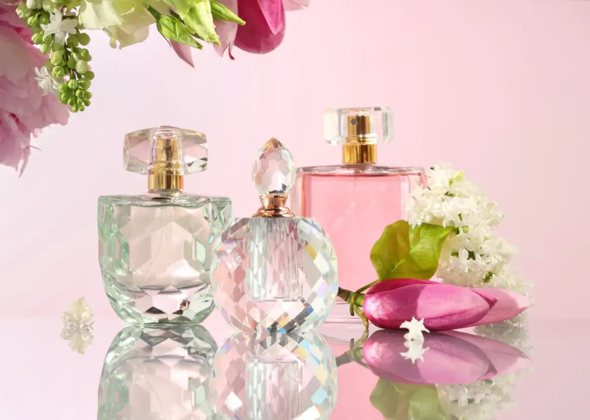 Eleganckie flakoniki perfum i woda toaletowa, otoczone kwiatami. Co lepsze woda toaletowa czy perfumowana? Wybór zależy od Ciebie!