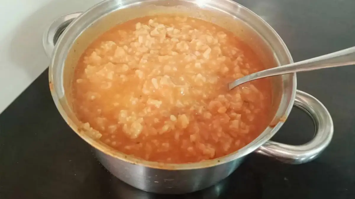 Gęsta zupa pomidorowa z ryżem w garnku, gotowa do podania. Idealna, by dowiedzieć się, jak zaprawić zupę pomidorową.