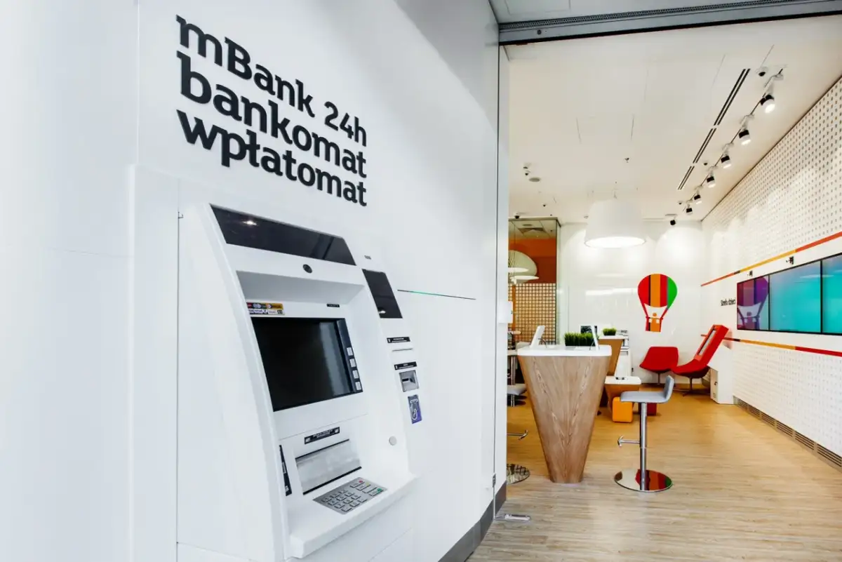 Wpłatomat mBank 24h, gotowy do obsługi o każdej porze. Wnętrze banku z nowoczesnym wystrojem.