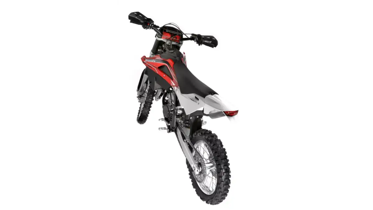 Husqvarna WR 125 gotowy do akcji. Czerwono-biały motocykl crossowy z grubymi oponami i wyścigowym designem.