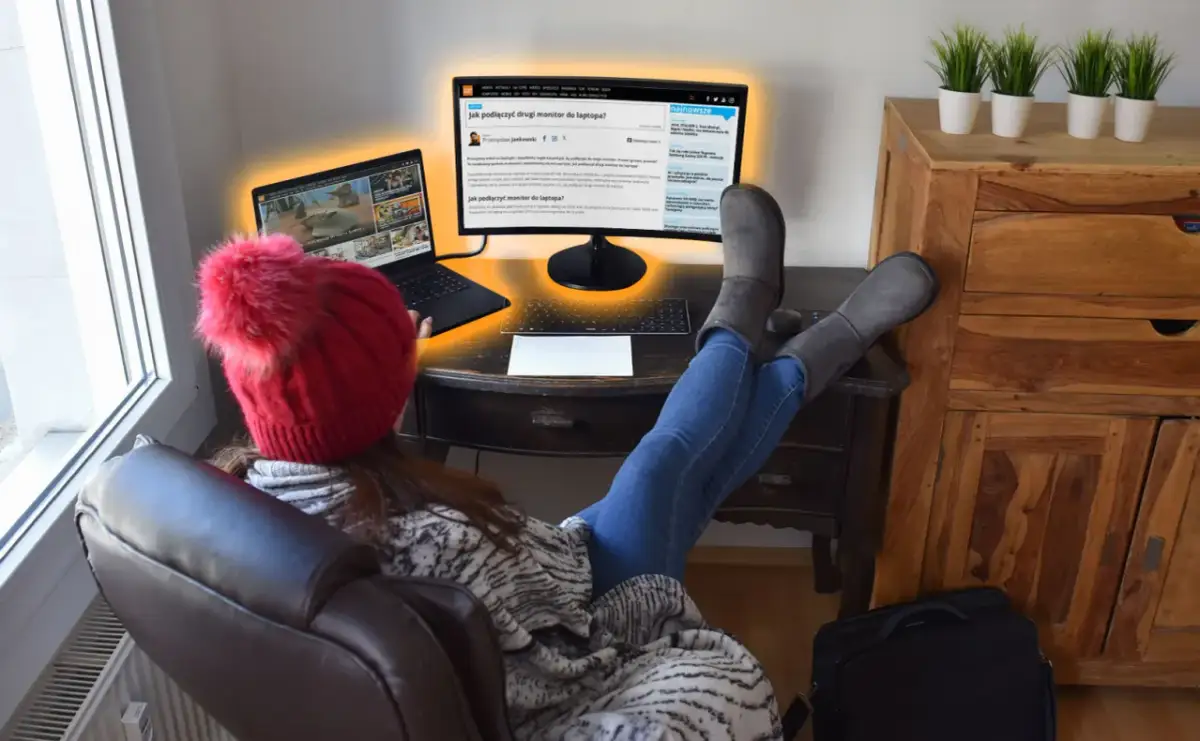 Osoba w czerwonej czapce z pomponem uczy się, jak podłączyć dwa monitory do laptopa, korzystając z artykułu na ekranie.