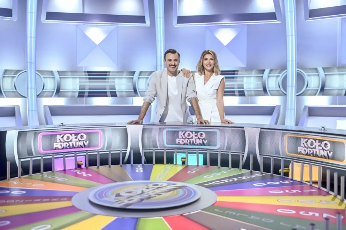 Prowadzący program "Koło Fortuny" stoją przy kole, gotowi do gry.