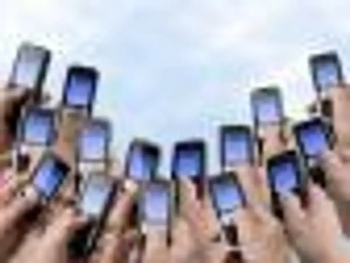 Ręce trzymają telefony komórkowe, gotowe do wysłania pustego SMS-a na loterię.