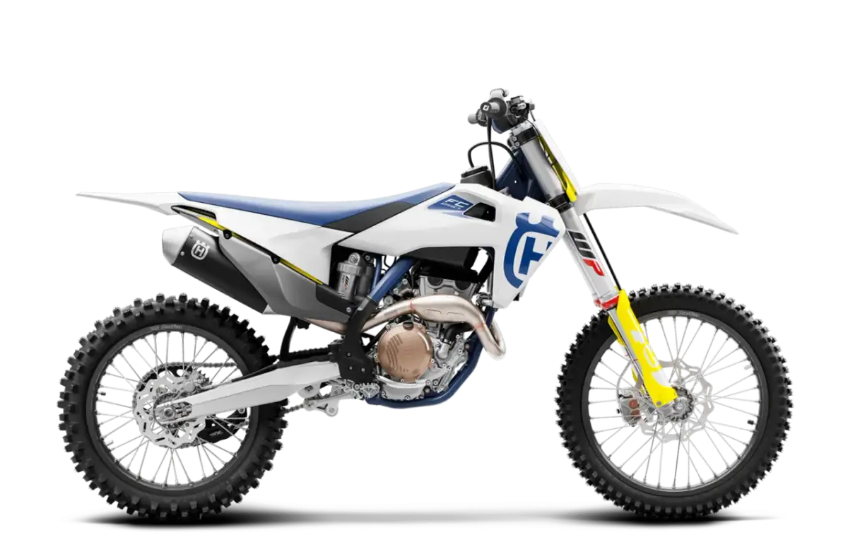 Biały motocykl Husqvarna FC 250 z niebieskim siedzeniem i żółtymi akcentami, gotowy do jazdy po torze.