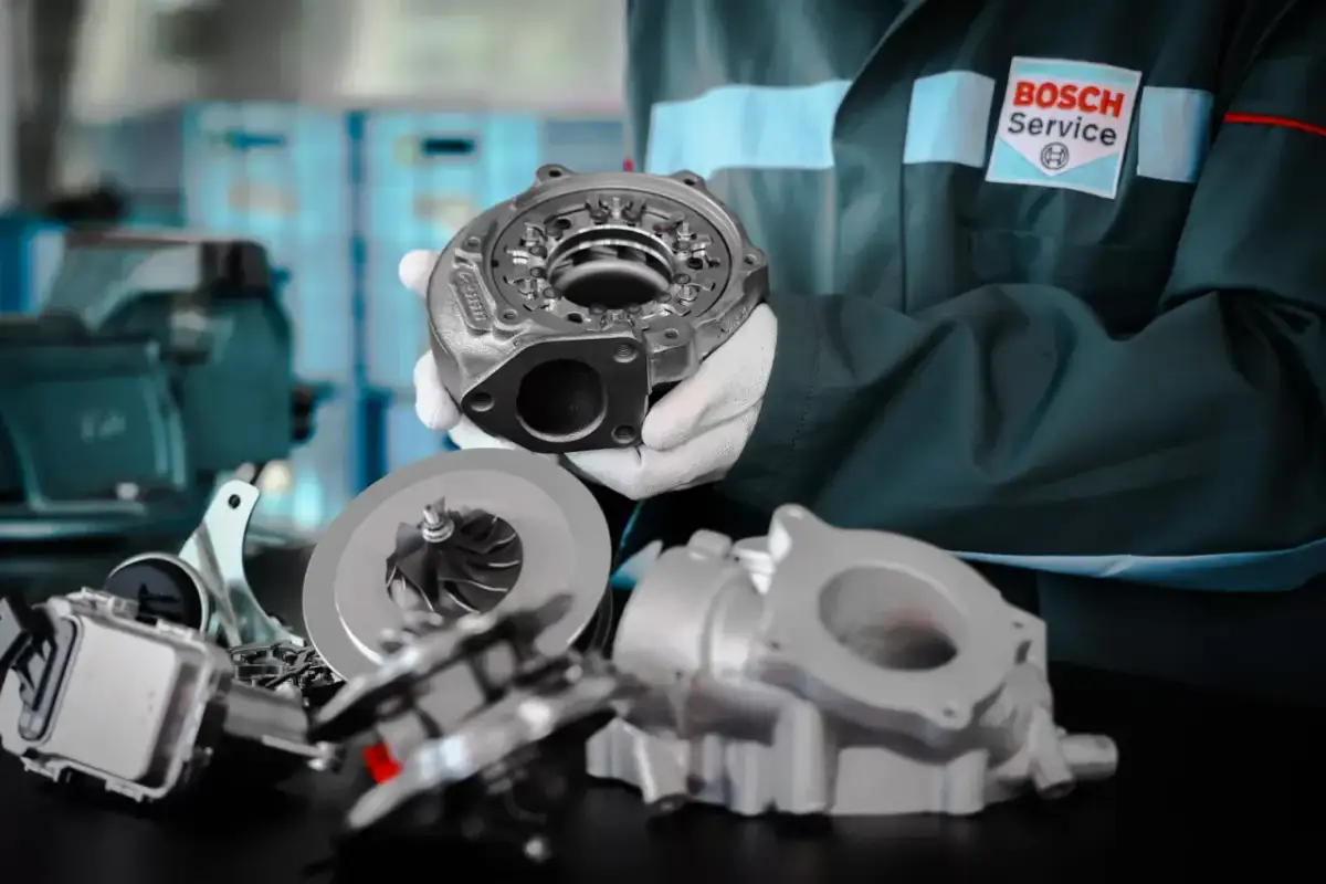 Mechanik w rękawiczkach pokazuje części turbosprężarki, kluczowego elementu, gdzie jest turbina w samochodzie.