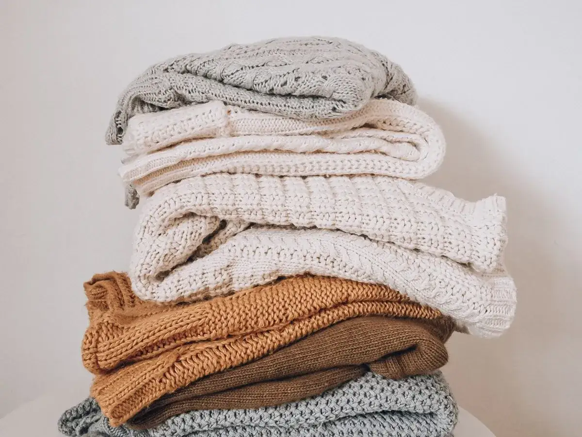 Stos ciepłych, dzianinowych swetrów w odcieniach beżu, brązu i szarości. Idealne na zimę, a jak prać akryl, by służyły latami?