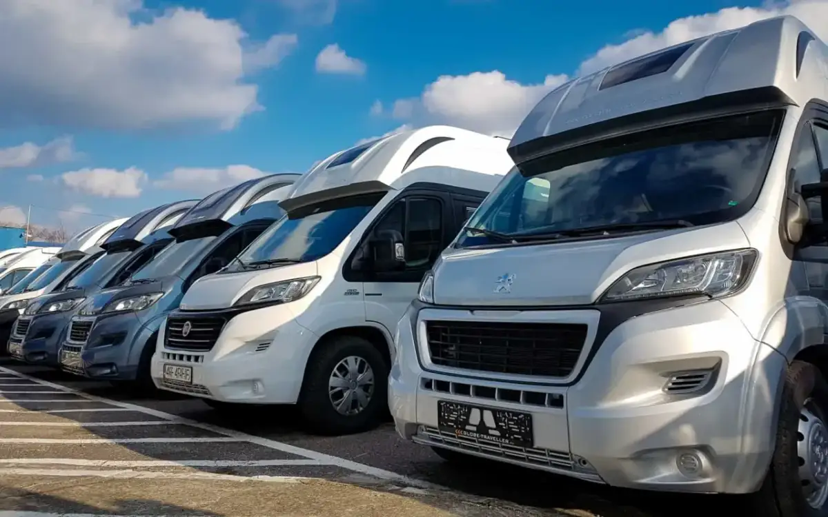 Rząd kamperów na parkingu, idealny na wakacje. Szukasz kamper tanio? Te pojazdy czekają na Ciebie!