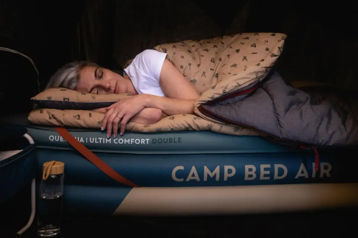 Kobieta śpi na dmuchanym materacu w namiocie, otulona śpiworem. Idealne rozwiązanie, na czym spać w namiocie, by czuć się komfortowo.