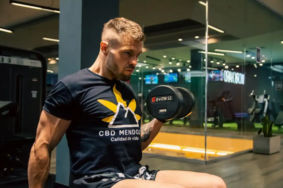 Mężczyzna ćwiczy z hantlem 15kg. Zastanawiasz się, ile trwa trening na siłowni? Kluczowe jest efektywne wykorzystanie czasu.