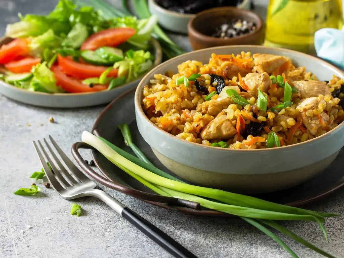 Pyszne kaszotto z kurczakiem, marchewką i śliwkami, podane z sałatką ze świeżych warzyw. Idealny obiad!