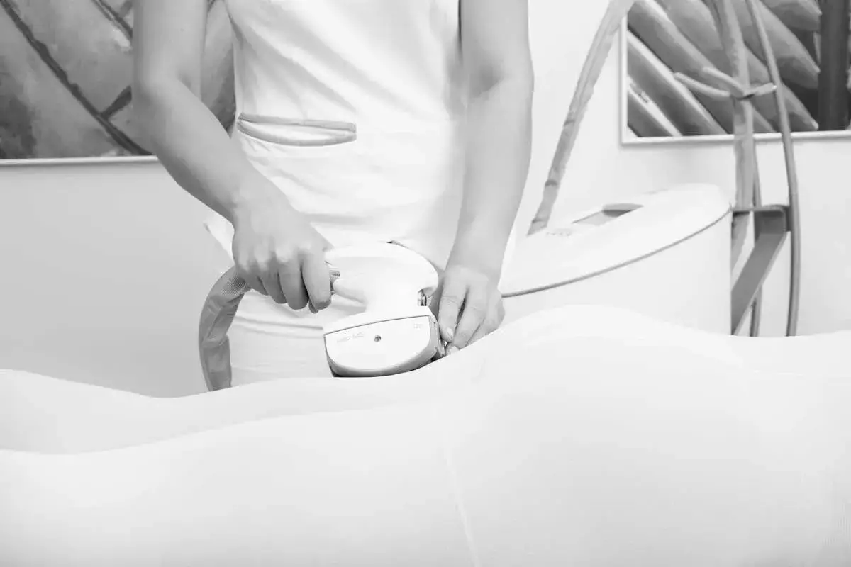 Zabieg endermologii z wykorzystaniem głowicy vacuum. Widoczne ręce terapeuty wykonujące masaż.