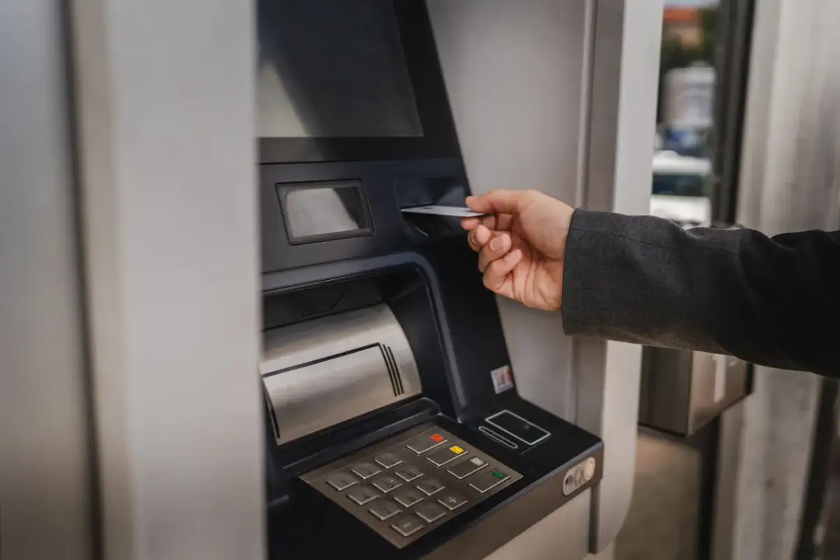 Dłoń wsuwa kartę do bankomatu PKO. Zastanawiasz się, ile można wyplacic w bankomacie PKO? Sprawdź to!