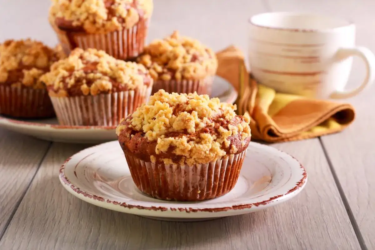 Pyszne muffinki drożdżowe z kruszonką na talerzykach, obok filiżanka kawy.