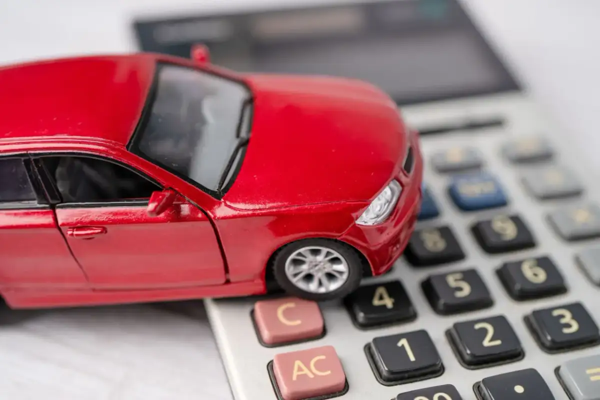 Czerwony model samochodu na kalkulatorze symbolizuje rozważania o wynajem samochodu od osoby prywatnej a podatek.