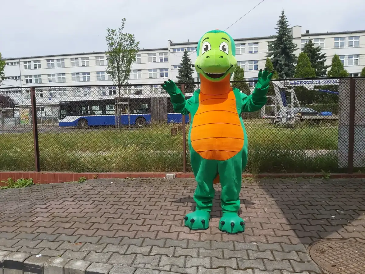 Zielony strój smoka z pomarańczowym brzuchem, stojący na chodniku.