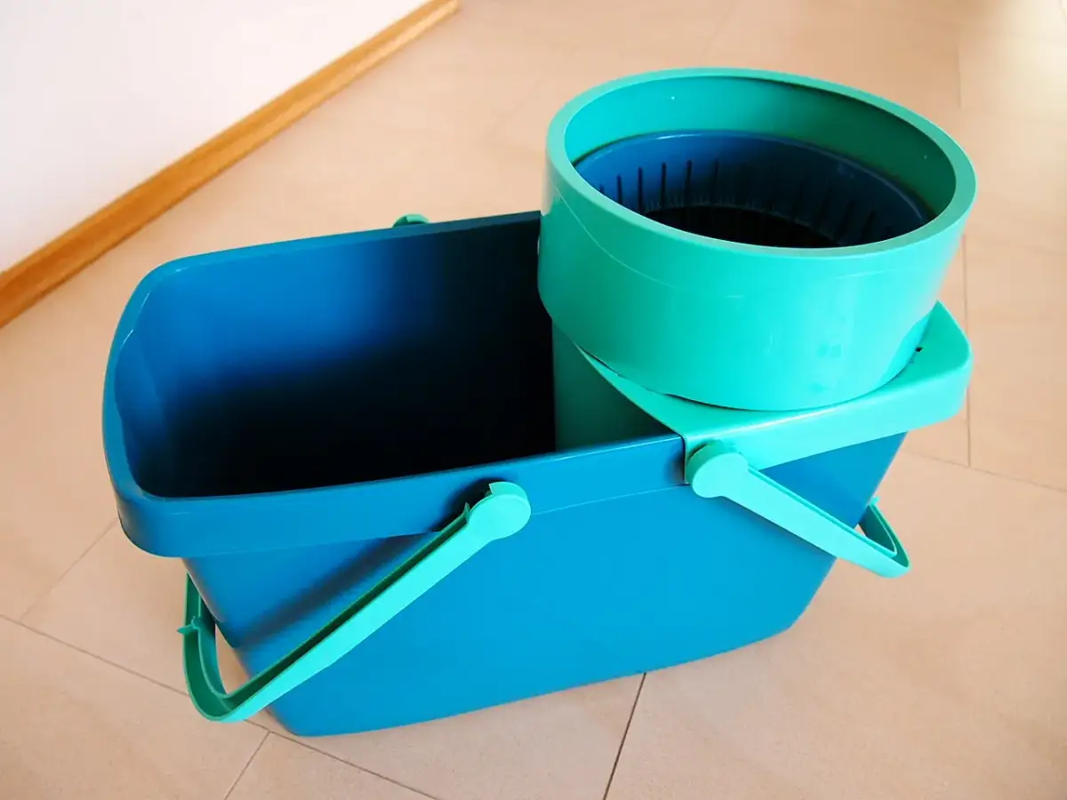 Niebieskie wiadro z zielonym wkładem do mopa obrotowego.