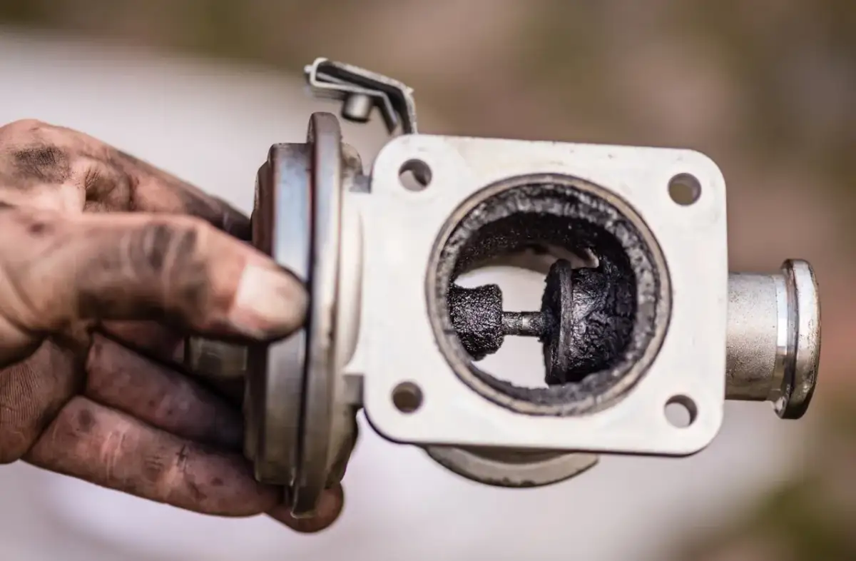 Brudny zawór EGR zablokowany w pozycji otwartej, z widocznym nagarem.