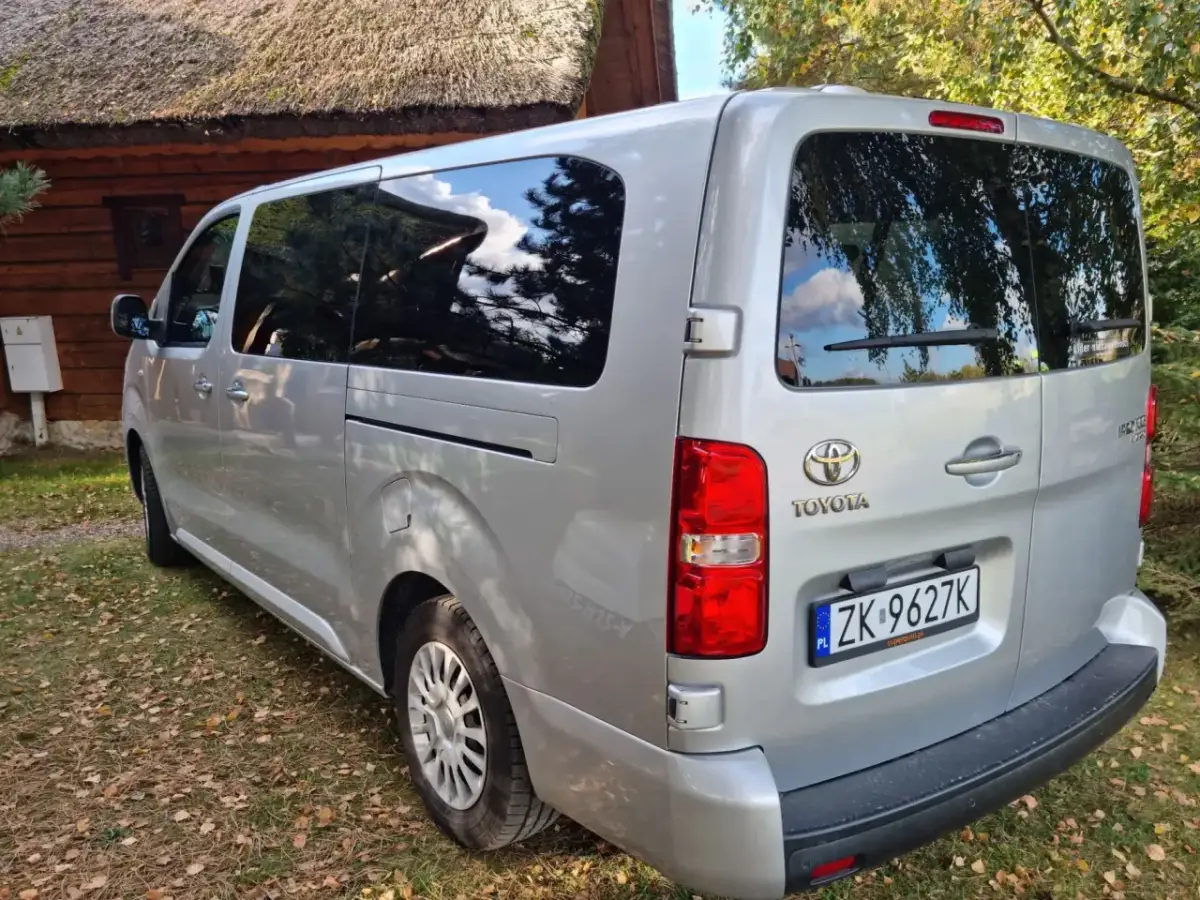 Srebrna Toyota z tablicą ZK 9627K, idealna na cesja leasingu. Zaparkowana przy drewnianym domu z krytym strzechą dachem.