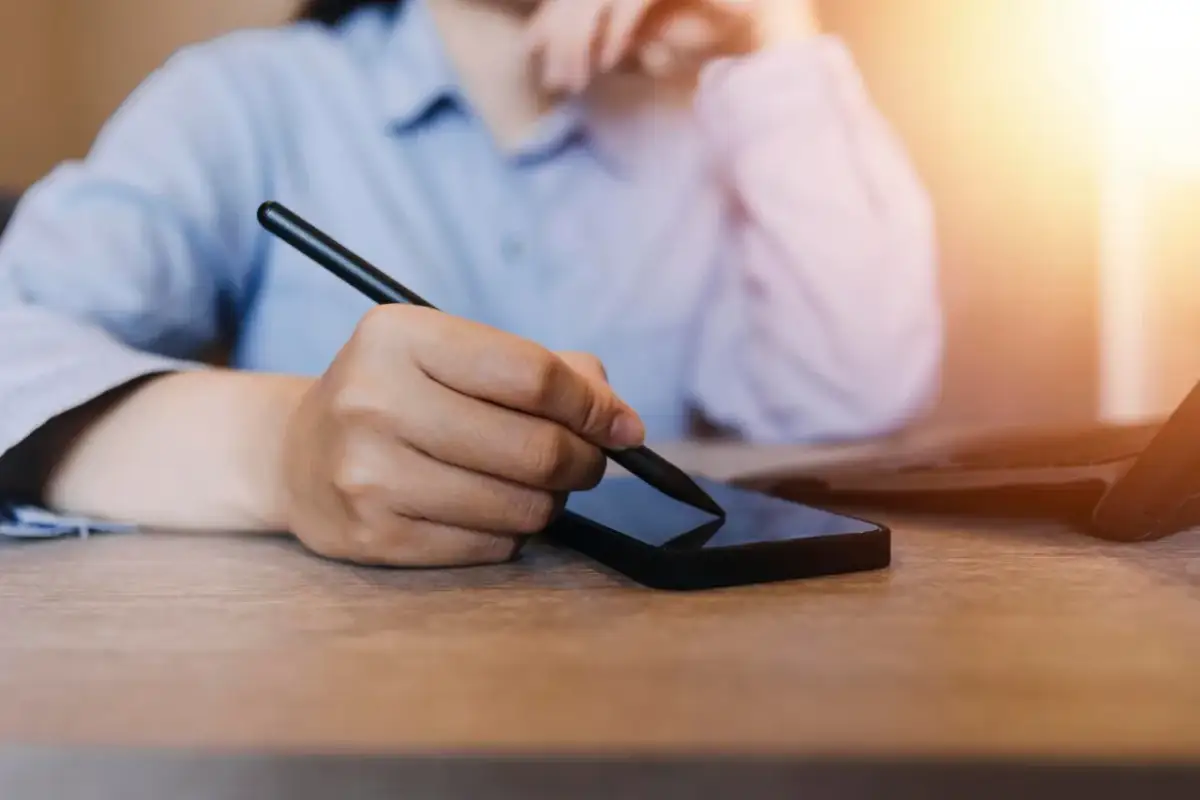 Osoba korzysta ze smartfona i rysika, szukając informacji, jak zmienić numer telefonu w mBank.