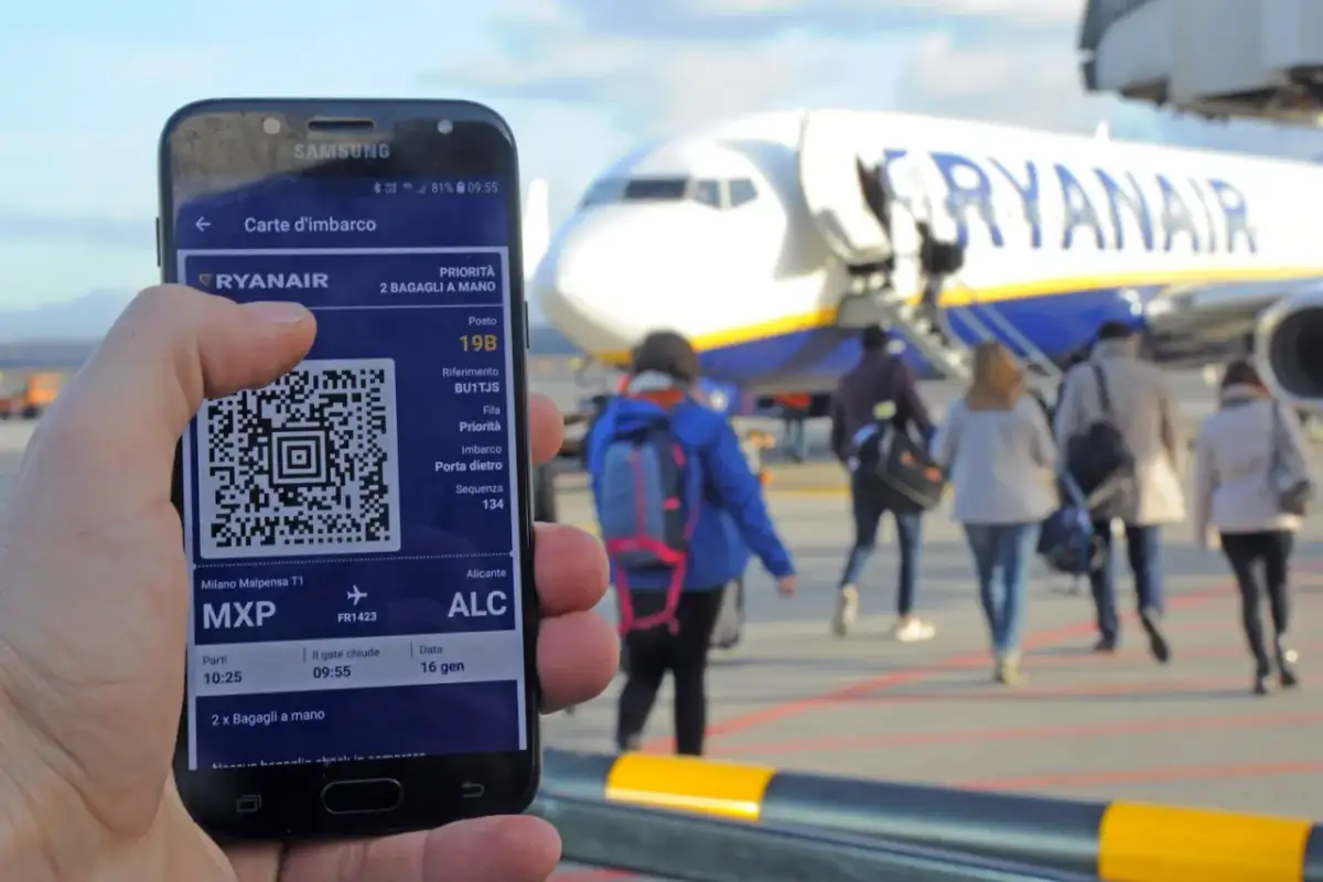 Telefon z kartą pokładową Ryanair i samolot na tle.
