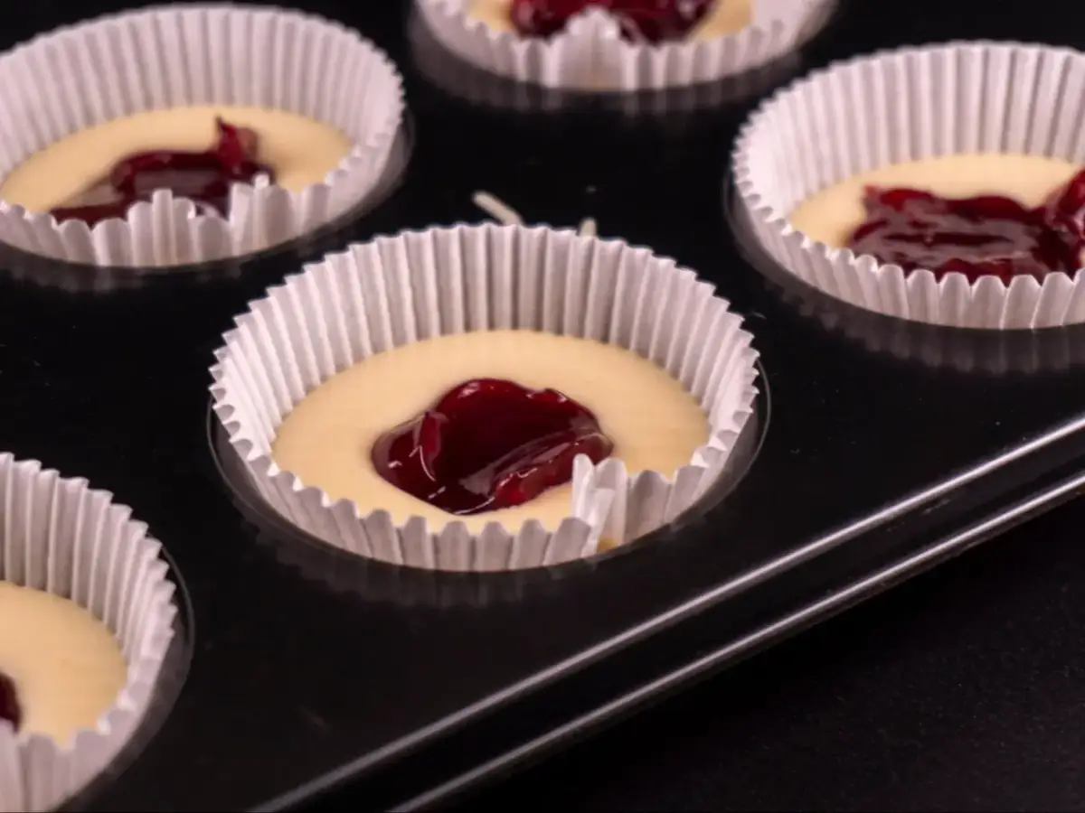 Nadziewane dżemem muffinki w papierowych foremkach w blaszce.