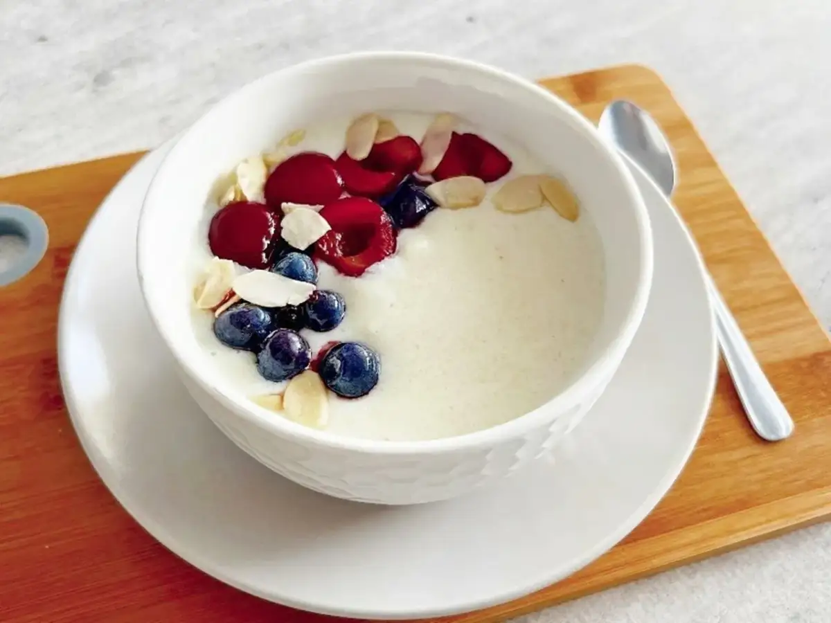 Pyszne śniadanie na słodko: kremowa owsianka z jagodami, wiśniami i płatkami migdałów. Idealny początek dnia!