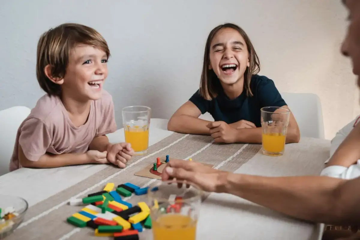 Dzieci śmieją się, grając w grę planszową. To świetna zagadka dla dziecka, pełna radości i zabawy.