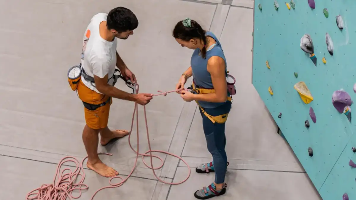 Para wspinaczkowa ćwiczy węzły wspinaczkowe przy ścianie.